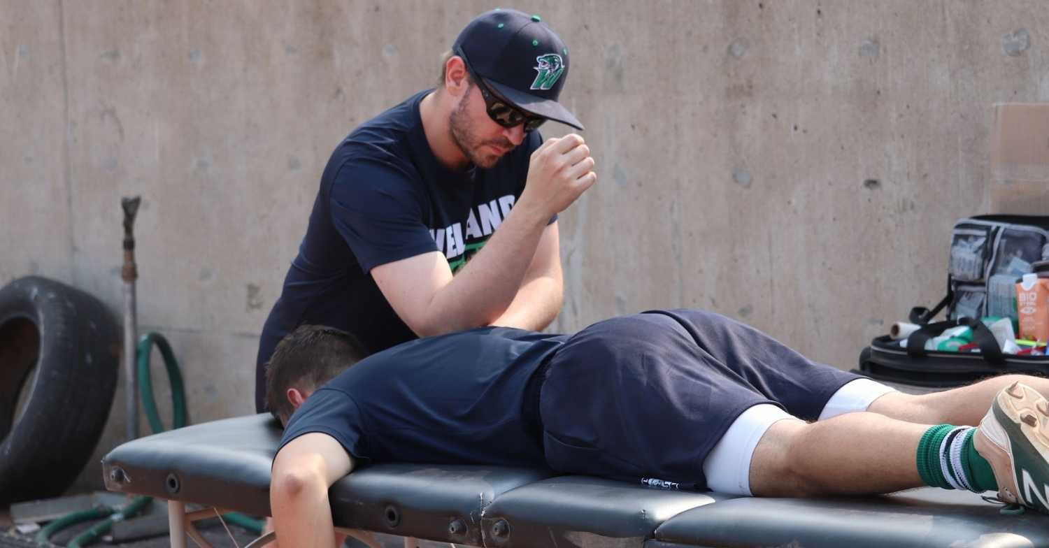 trevor kwolek sports physiotherapist working on welland jackfish baseball player's back before a game